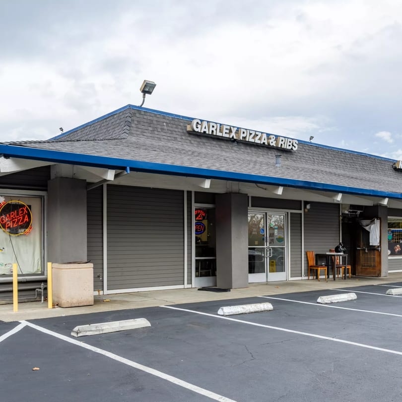 Exterior of Garlex Pizza & Ribs restaurant with a parking lot in the foreground.
